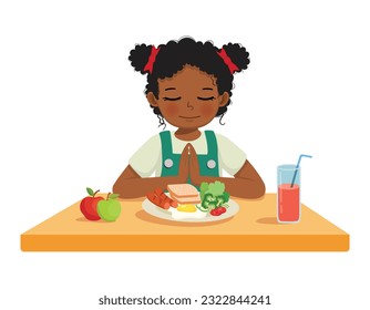 Cute little African girl praying before eating breakfast at the table