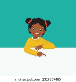 Cute little African girl standing behind blank board pointing to empty banner with finger