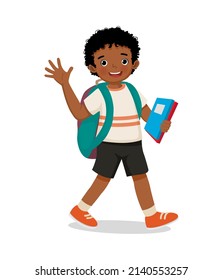 cute little African school boy with backpack holding books walking to school waving hand