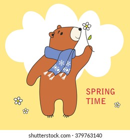 The cute little bear smells a flower on a spring meadow