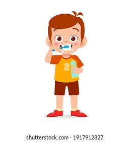 cute little boy brushing teeth and holding toothpaste