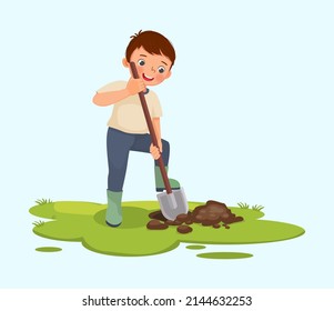 Cute little boy digging hole on the ground with shovel in the garden