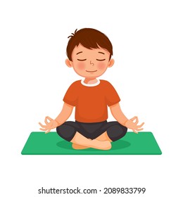 Cute little boy doing gymnastic fitness exercises practicing yoga meditation sitting in lotus pose on a mat indoor