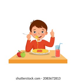 Cute little boy eating delicious spaghetti using fork showing thumb up gestures.