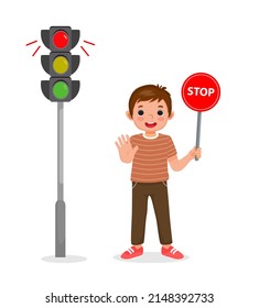 cute little boy holding stop sign board showing traffic light indicator red light on 