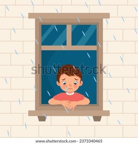 Cute little boy looking at raindrops from window feeling sad can not play outside