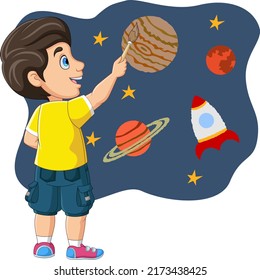 Cute little boy painting rocket, stars, and planets on the wall
