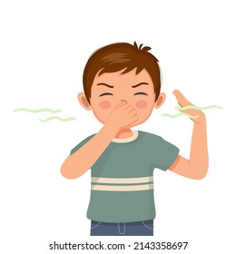 cute little boy pinching and cover his nose smelling something stinky and bad aroma holding breath with fingers on nose