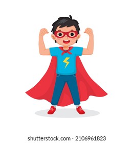 Cute little boy playing dressed in superhero costumes standing raising hands showing strong arms