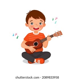 Cute little boy  playing ukulele or  guitar singing sitting on floor with smiling facial expression