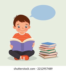 Cute little boy reading a book sitting on the floor beside stack of books