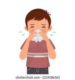 Cute little boy sneezing with flu and cold allergic symptoms blowing nose into tissue paper