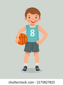 cute little boy with sportswear holding basketball standing posing with hand on his waist