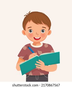 Cute little boy student holding pen and notebook writing making note