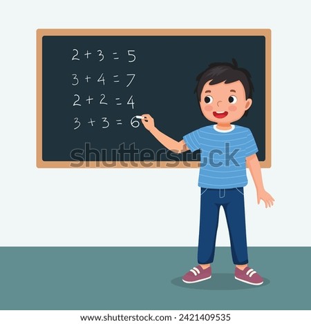 Cute little boy student write on blackboard math equation in front of class with chalk