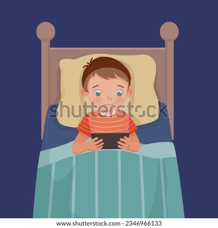Cute little boy using smartphone lying on the bed at night