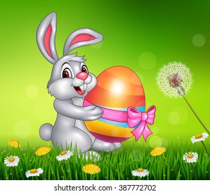 Cute little bunny holding easter egg on grass background