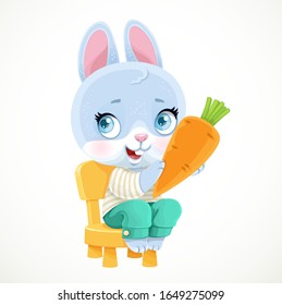 Cute little bunny sitting on a chair and holding carrot in paws isolated on white background.