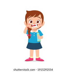 cute little girl brushing teeth and holding toothpaste