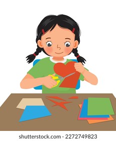 Cute little girl cutting colored paper with scissors making heart shape paper cut art craft