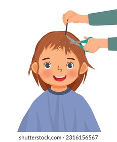 Cute little girl getting hair cut by hair dresser in the hair salon