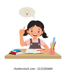 Cute little girl have an idea to solve the problems in math homework raising her index finger pointing up while sitting studying on the desk at home