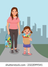 Cute little girl helping her mother carrying grocery bag