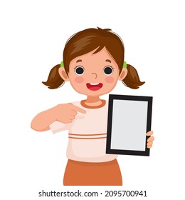 cute little girl holding digital tablet with finger pointing to empty screen or copy space for texts, messages and advertising content. Kids and electronic gadget devices concept for children.