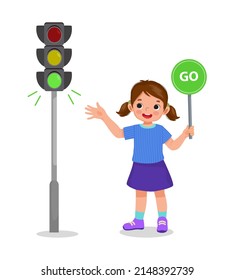 cute little girl holding go sign board showing traffic light indicator green light on