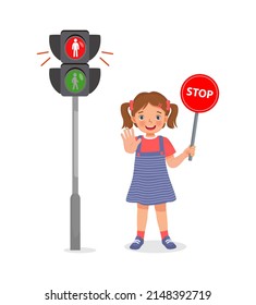 cute little girl holding stop sign board near pedestrian traffic light with indicator  red light on
