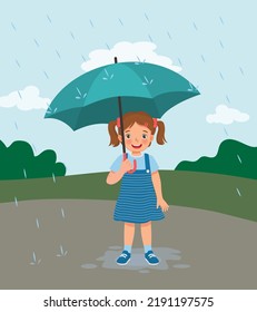 cute little girl holding umbrella in the rain on rainy day at the park