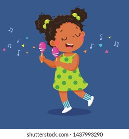 Cute little girl playing the maracas on blue background