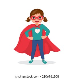 Cute little girl plays wearing superhero costumes standing with hands on her hips pose