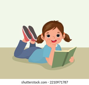 Cute little girl reading book lying on floor