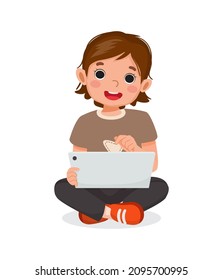 Cute little girl sitting on floor using digital tablet touching screen browsing internet, doing homework, and playing games. Kids and electronic gadget devices concept for children.