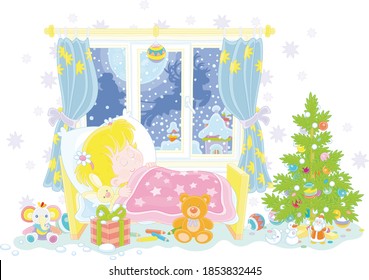 Cute little girl sleeping in her small bed on the night before Christmas, in a window of a nursery room magic reindeers flying Santa Claus with holiday gifts in his sleigh over snowy town