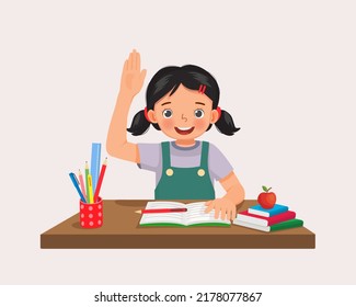 Cute little girl student rising hand asking question sitting at her desk in the classroom