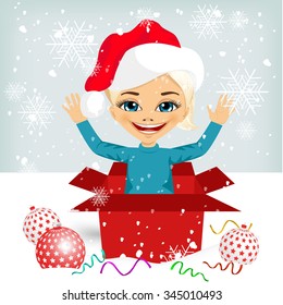 cute little girl wearing christmas hat coming out of inside christmas red gift box