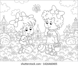 Cute little girls playing with a small toy rabbit among flowers on grass of a lawn against a background of houses of a small town, black and white vector illustration in a cartoon style