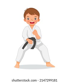 cute little karate kid boy with black belt showing hand defense techniques poses in martial art training practice