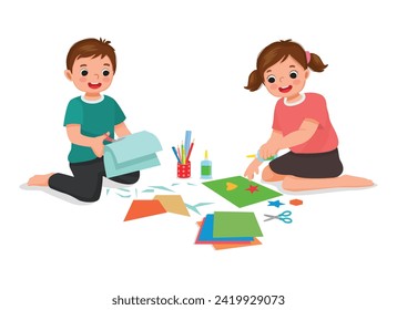 Cute little kids cutting paper making art sitting on the floor together