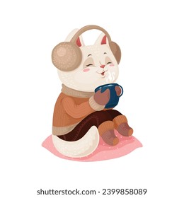 Cute little kitten in jumper and socks listening to music and drinking hot chocolate from a mug