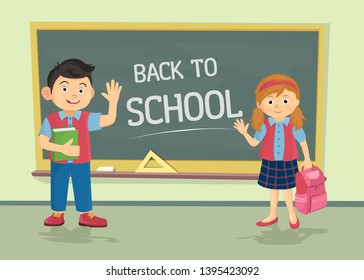 Cute little schoolgirl and schoolboy wearing uniform with backpacks standing near blackboard with copy space isolated on white background.