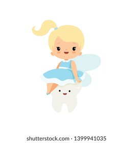 Cute Little Tooth Fairy Sitting on Baby Tooth, Lovely Blonde Fairy Girl Cartoon Character in Light Blue Dress with Wings Vector Illustration