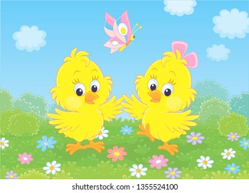 Cute little yellow chicks dancing with a butterfly among flowers on green grass of a lawn on a sunny day, vector illustration in a cartoon style