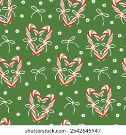 Cute red candy canes with bows, berries and holly plant berries seamless pattern on green. Holiday season festive background. Elegant design for wrapping paper, fabric.