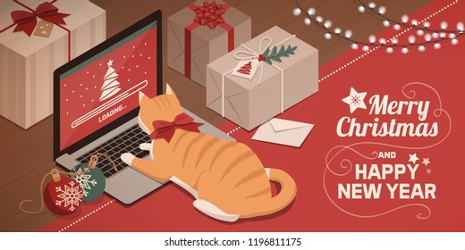 Cute red cat lying on the laptop keyboard and watching Christmas app loading on the screen