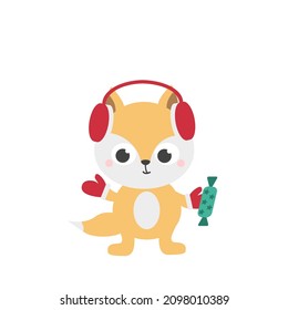 A cute red fox cub in red headphones and mittens holds a green chocolate candy. Christmas cute character. Merry Christmas. Vector illustration. Greeting card, sticker or banner.