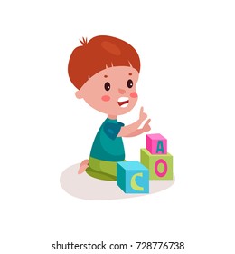 Cute redhead little boy sitting on the floor playing with block toys, kid learning through fun and play colorful cartoon vector Illustration