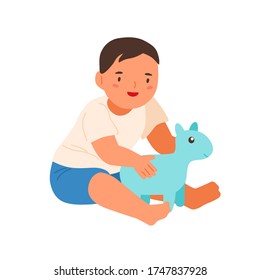 Cute smiling child playing with soft toy vector flat illustration. Happy little boy sitting hugging plaything isolated on white background. Adorable baby enjoying childhood having positive emotion